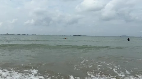 Ocean Wave Crashing on Beach with Distant Cargo Ships and Swimmer Stock Footage 330933093