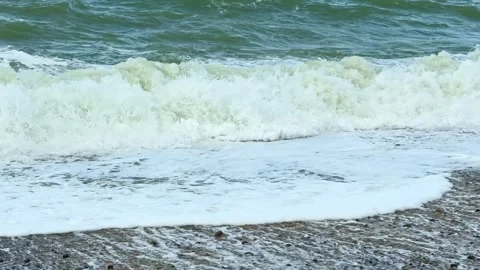 Ocean wave crashing on a pebble beach in slow motion Stock Footage 332595989