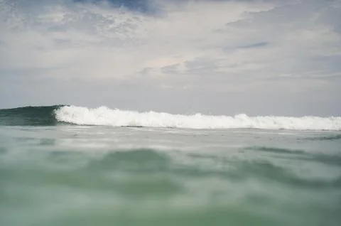 Ocean wave cresting under cloudy sky Stockfoto's