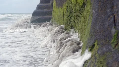 OCEAN WAVE FOAM HITTING ROCK WALL ON BEACH Stock Footage 272509772
