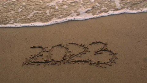 Ocean wave leaves text 2023 on the sand. Stock Footage 227697772