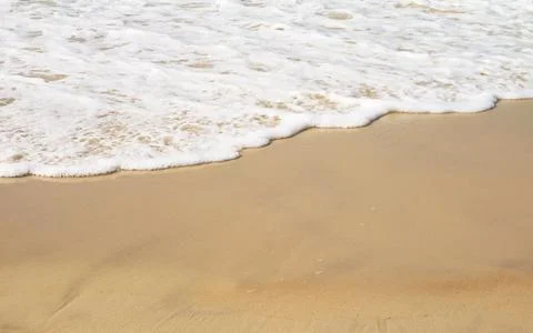 Ocean wave spilling on calm sandy shore Stock Photos
