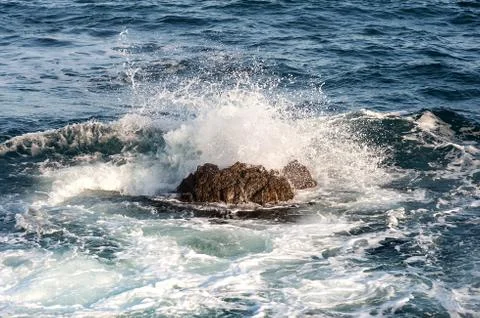 Ocean wave splashing when hit at a large stone in the water Splash High Stock Photos
