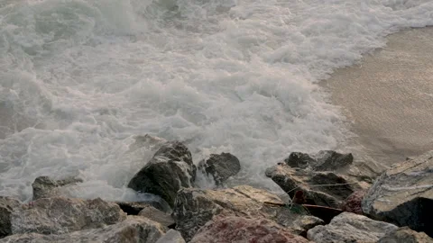 Ocean wave surges in slow motion and crashes against large shoreline rocks with Stock Footage 307696129