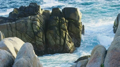 Ocean wave washes around big rock formation scored and cut by erosion Stock-Footage 123565224