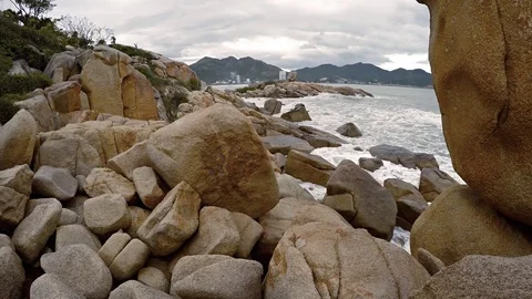 Ocean Waves and Foam along a Rocky Urban Beach in Vietnam 库存影片 74980526