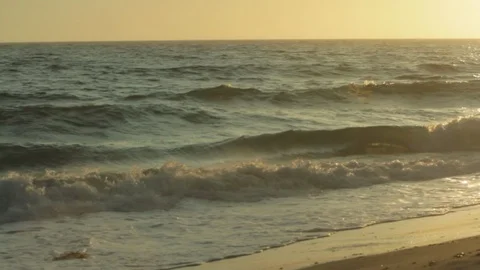 Ocean waves and sunset. Beach front view of sun hitting water. pan A Stock Footage 102403551