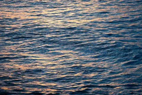 Ocean waves and the water surface at sunset Stock Photos