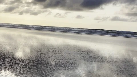 Ocean Waves and Wet Sand Reflection Under Cloudy Sky Cinematic 4K Vídeo Stock 333783456