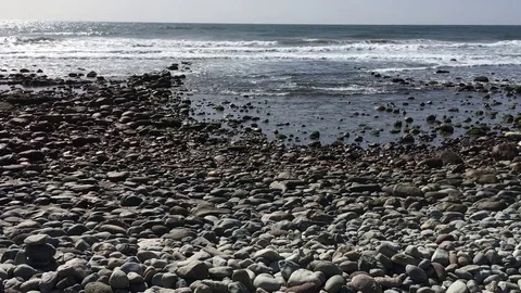 The Ocean waves bathe the pebbled shore Stock Footage 74136938