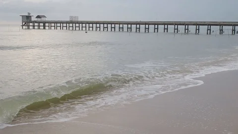 Ocean waves at the beach with a bridge in the background on a dark sky Stock Footage 129349827