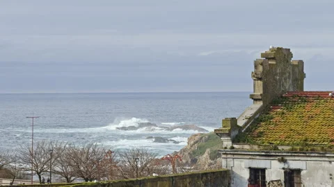 Ocean waves beside coastal building Stockbeeldmateriaal 338294486