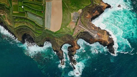 Ocean waves break inside rocky inlet below basalt cliffs on Azores Island Stock Footage 340068975