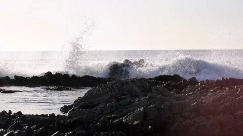 Ocean waves breaking against rocky shoreline at sunset 2 Stock Footage 87279436