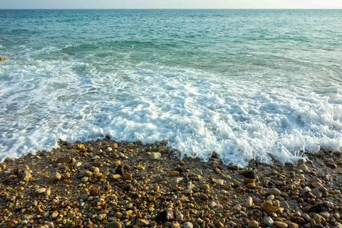 Ocean waves breaking on a beautiful pebble shoreline white foam bubbles tur.. Foto stock
