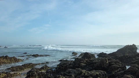 Ocean waves breaking over rocky shore in summer. Pan right. Stock Footage 194199532