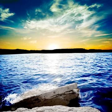 Ocean waves breaking on a rock with sunset Stock Photos