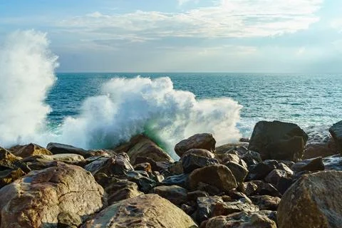Ocean waves breaking on rocks at sunset Stock Photos