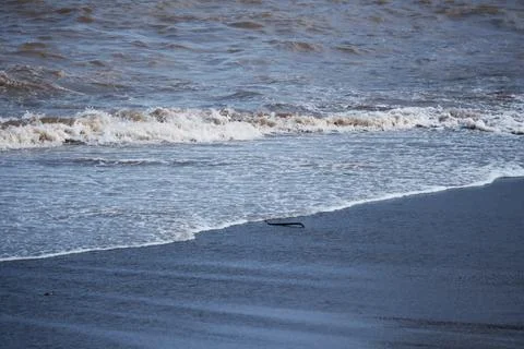 Ocean waves breaking upon a sandy beach Stock Photos