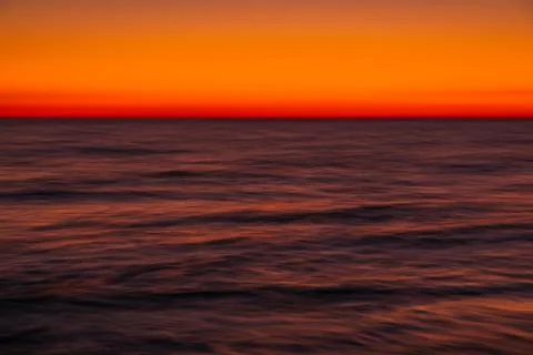 Ocean with waves at bright sunset or sunrise shooting with long exposure Stock Photos