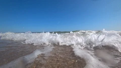 Ocean waves cover a camera on a beautiful sandy beach on a sunny summer day. Stock Footage 87543633