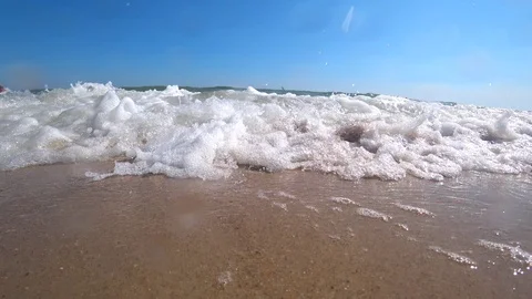 Ocean waves cover a camera on a beautiful sandy beach on a sunny summer day. Stock Footage 87543669