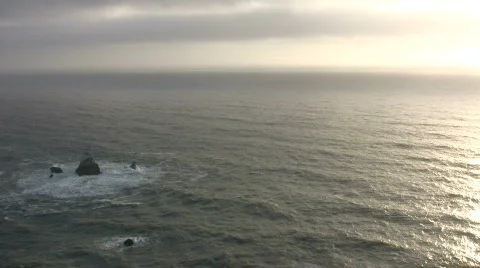 Ocean waves crash against rocks amidst the reflected sunlight Stock Footage 360352