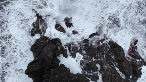 Ocean waves crash against rocky shoreline, creating foam and splashes Stock Footage 328528367