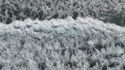 Ocean waves crash and recede in a rhythmic pattern, showcasing the dynamic flow Видео 334130282