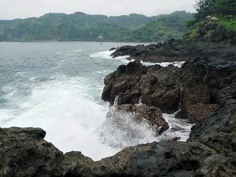 Ocean waves crash beautifully against the rocks on the beach Stock Photos