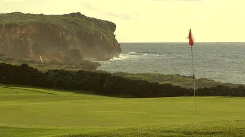 Ocean waves crash onto cliff behind golf course putting green A Stock Footage 125332686