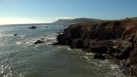 Ocean waves crash onto cliff rocks at empty island beach Stock Footage 125341177