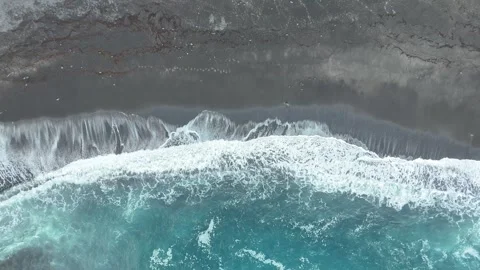 Ocean waves crash onto dark sandy beach, creating foam and ripples Stock Footage 328298378