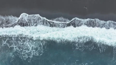 Ocean waves crash onto dark sandy beach, creating foam and ripples, with a clear Видео 335876932