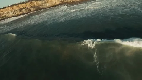 Ocean waves crash near rugged cliffs under clear blue sky Stock Footage 339792167