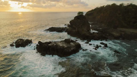 Ocean waves crash over dark rocks during sunset at Ostional Beach Costa Rica Stock Footage 345540600