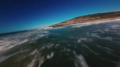 Ocean waves crash powerfully against shore under clear blue sky Stock Footage 339786150