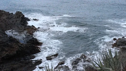 Ocean waves crash on the rocks of the island's coast. HD video Stock Footage 98564309