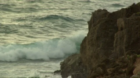 Ocean waves crash onto rocks on shore island beach at sunset Stock Footage 125332907