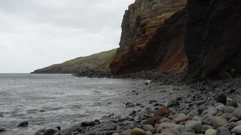 Ocean Waves Crash on Rocky Beach with Cliff Landscape Under Overcast Sky Stock Footage 334591700