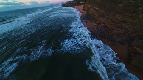 Ocean waves crash onto rugged cliffs at twilight Stock Footage 340915064
