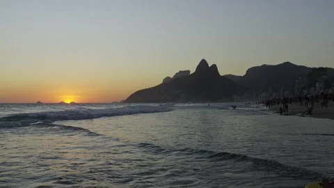 Ocean Waves Crash on Sandy Beach at Sunset with Mountains in Distance Stock Footage 334815733