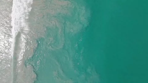 Ocean waves crash onto sandy shore, creating ripples and foam patterns Vídeos de archivo 340407445