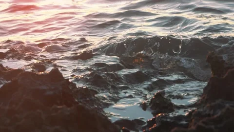 Ocean waves crash softly against rocky coast in golden sunlight. Stock Footage 337409534