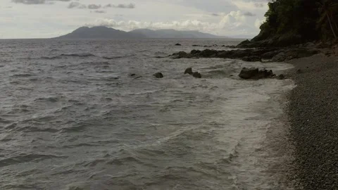 Ocean waves crash spread whitewash foam on pebble looc beach, perfect Vidéo 250969702