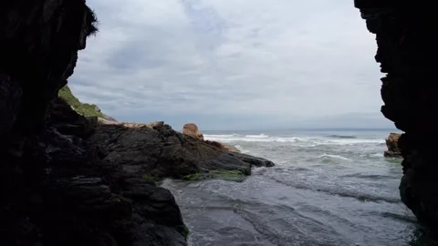 Ocean Waves Crash by Stone Formations and Cliffs on an Overcast Day Stock-Footage 336452711