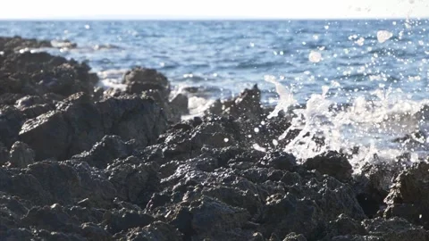 Ocean waves crash violently against dark rugged rocks during daytime. Stock Footage 337412219