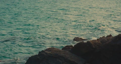 Ocean waves crashing against dark volcanic rocks along the coastal shoreline 動画素材 342579572