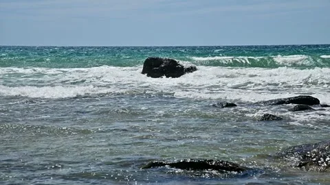 Ocean waves crashing against dark rocks on shoreline Stock Footage 345160556