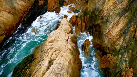 Ocean Waves Crashing Against Jagged Coastal Rocks on a Sunny Day Stock Footage 341999136